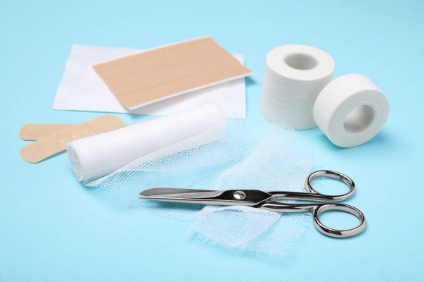 White bandage and medical supplies on light blue background